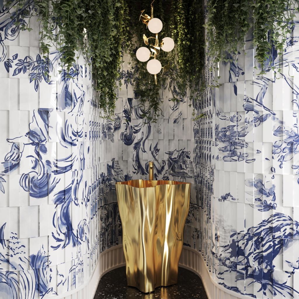 Luxury powder bathroom featuring the Eden Pedestal Sink in sculptural gold, hand-painted blue and white ceramic tiles, Hera Pendant Lamp, cascading greenery, and black terrazzo flooring, creating a contemporary and nature-inspired retreat.